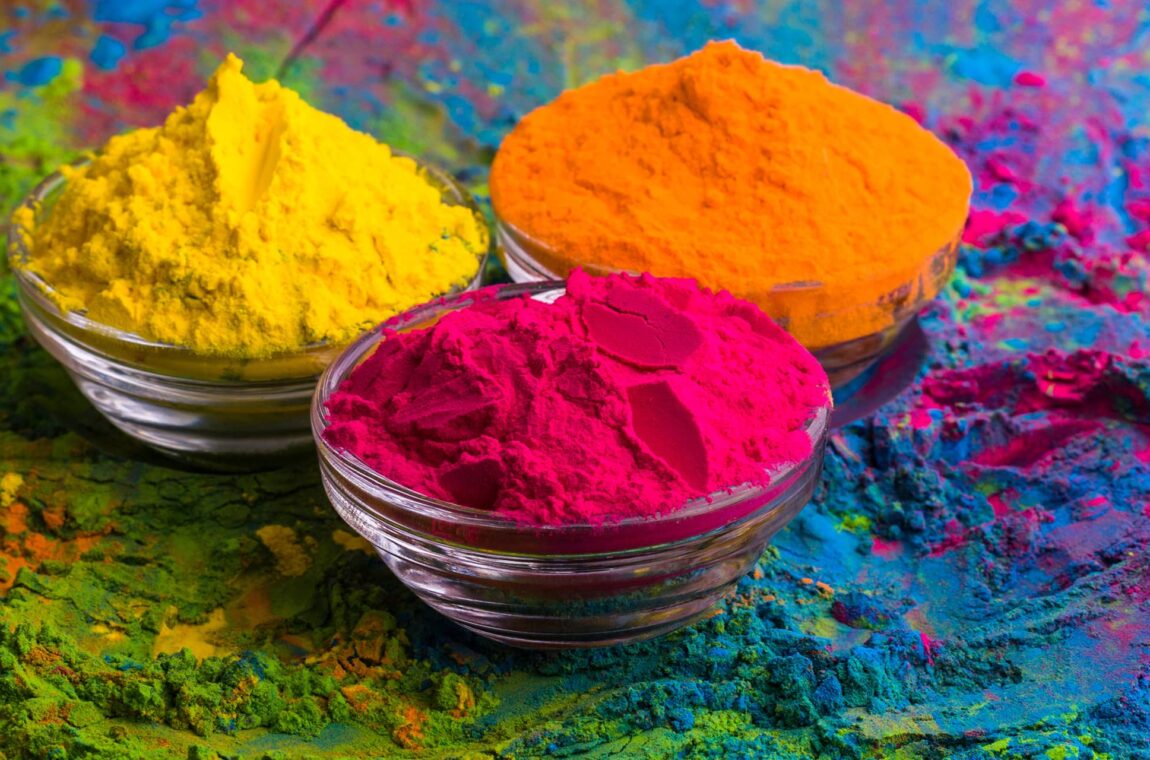 various color pigments yellow-orange-pink in glass bowls and pink, blue-green powder on wooden base